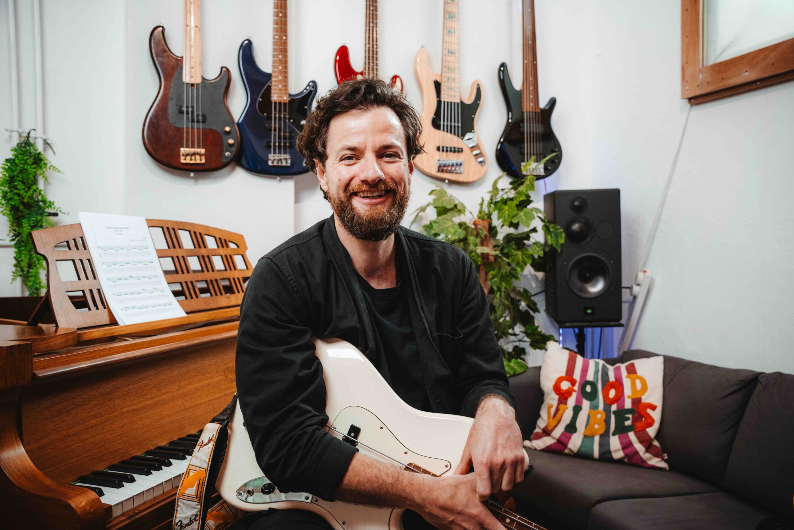 Bass teacher giving lessons in Leith, Edinburgh in a recording studio with a baby grand piano and a collection of basses.